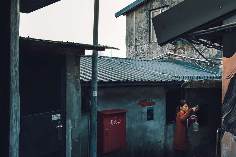 Photo de rue en couleur d'une femme prenant une photo avec son téléphone portable dans une ruelle à Taipei, Taiwan.