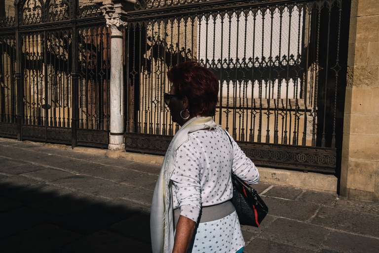 Photo de rue en couleur d'un dame bien habillée marchant devant une église dans les rues de Cordoue, en Espagne.