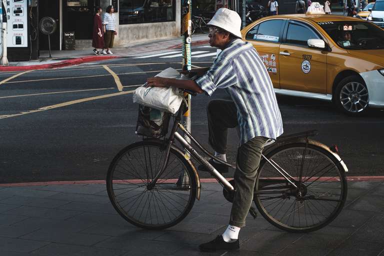 Photo de rue en couleur d'un vieil homme bien habillé à vélo avec un chapeau à Taipei, Taiwan.