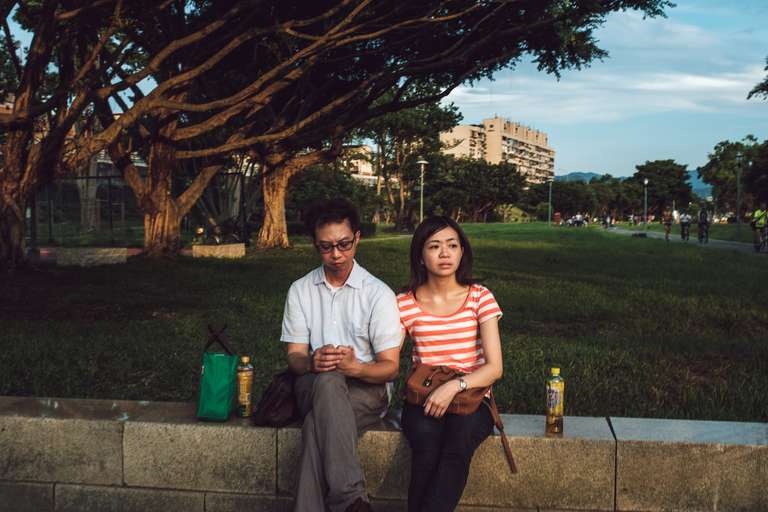 Photo de rue en couleur d'un couple assis sur un muret de pierre dans un parc à Taipei, Taiwan.