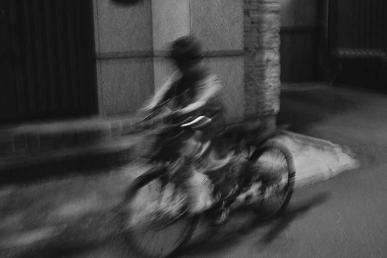 Photo de rue en noir et blanc d'un enfant à vélo dans une ruelle de Taipei, Taiwan.