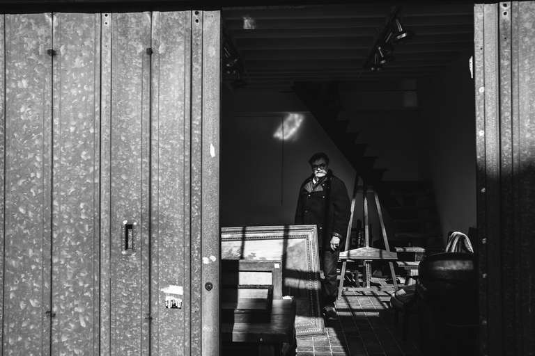 Photo de rue en noir et blanc d'un homme dans un garage d'un marché au puce de Paris, en France.