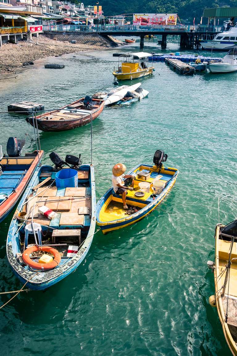 Photo en couleur d'un pécheur sur son petit bateau coloré sur l'île de Lantau à Hong Kong.