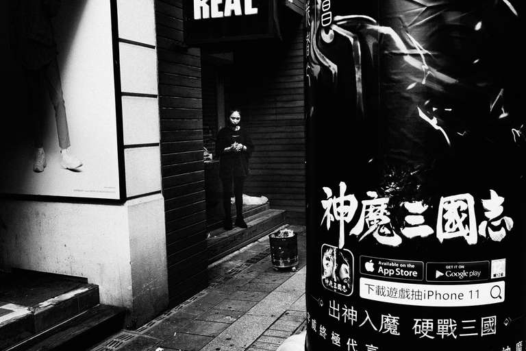 Photo de rue en noir et blanc d'une femme brulant de l'argent pour fantômes dans une rue de Taipei, Taiwan.