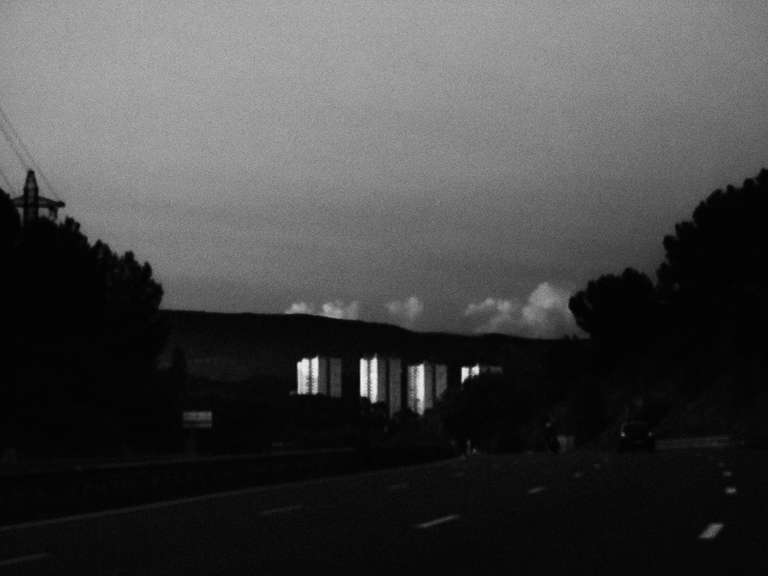 Photo de rue en noir et blanc d'une barre d'immeuble vu depuis l'autoroute au coucher du soleil à Toulon dans le sud de la France.