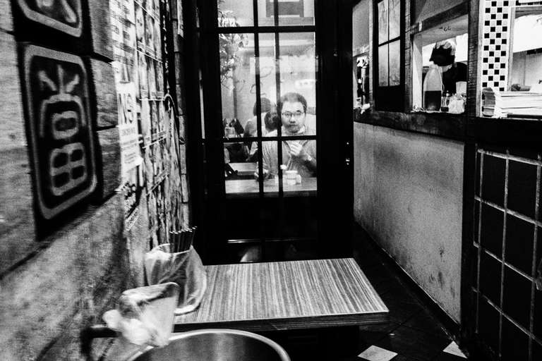 Photo de rue en noir et blanc d'un homme mangeant dans un restaurant très étroit à Taipei, Taiwan.