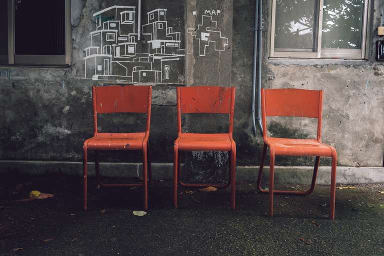 Color photography, a picture of three red chairs in front of a concrete wall with drawings on it in Taipei, Taiwan.
