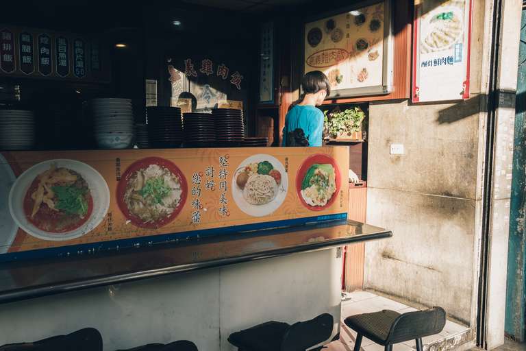 Color street photography. A picture of a young man at a restaurant, seen from outside, in Taipei, Taiwan.