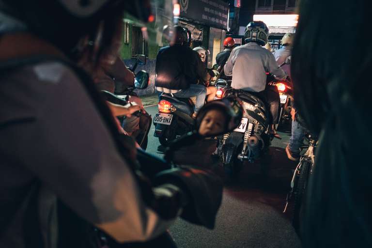 Color street photography. A picture of a lot of people driving scooters at night in the streets of Taipei, Taiwan.