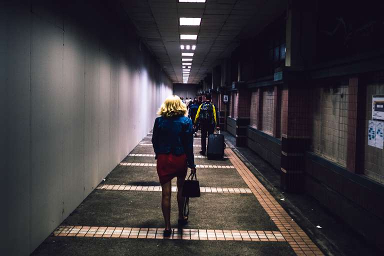 Color street photography. A picture of a woman walking down a corridor in Hong Kong.