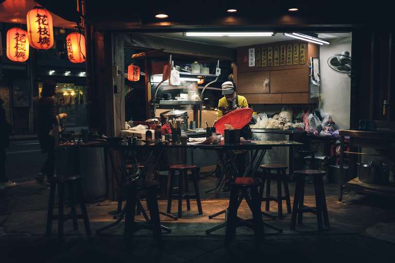 Color street photography. A picture of a street food restaurant with a busy cook at night in the streets of Taipei, Taiwan.