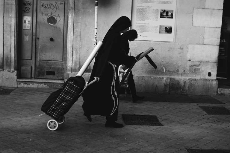 Black and white street photography. A picture of a couple of nuns dressed in black robes, walking in a street of Toulon, south of France.