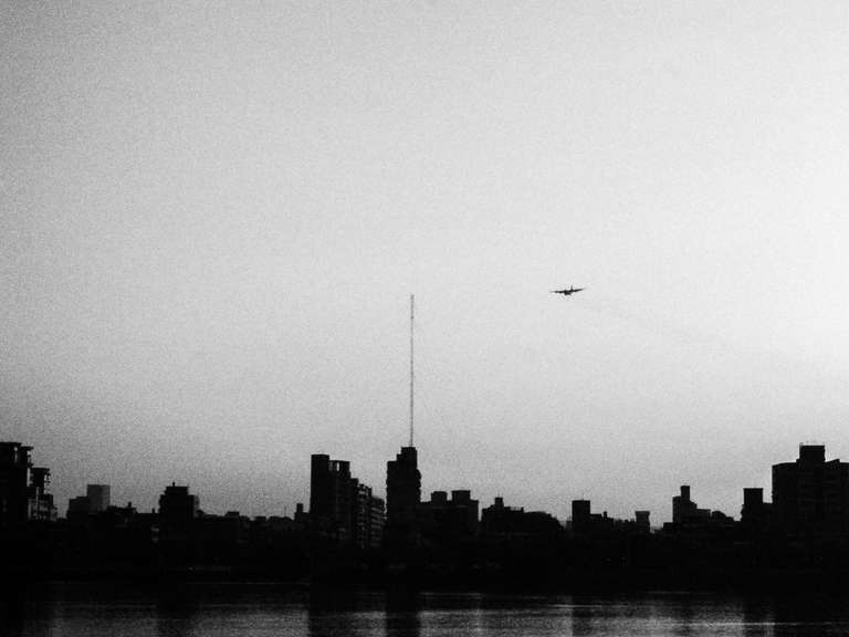 Black and white street photography. A picture of a plane flying over Taipei's skyline in Taiwan.