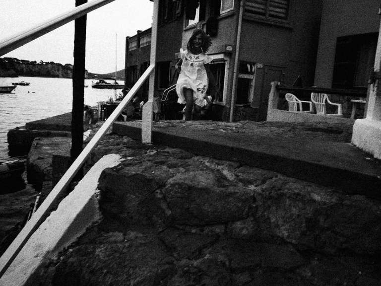 Black and white street photography. A picture of a young girl running on a little fisher village in Toulon, south of France.