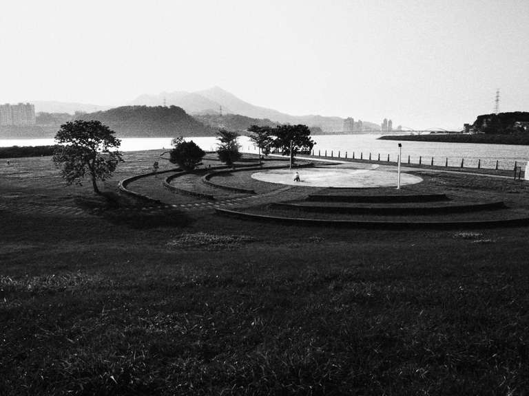 Black and white street photography. A picture of a park on Tamsui river's shore in Taipei, Taiwan.