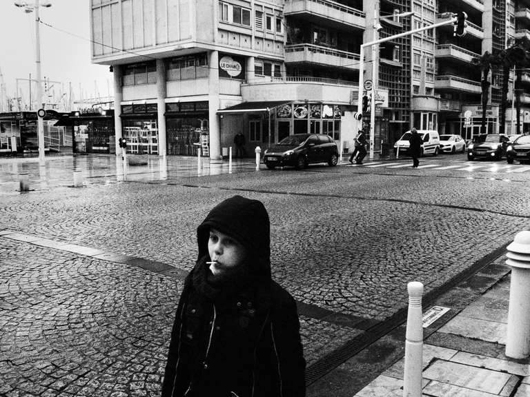 Black and white street photography. A picture of a kid, near Toulon's port, under the rain in south of France.