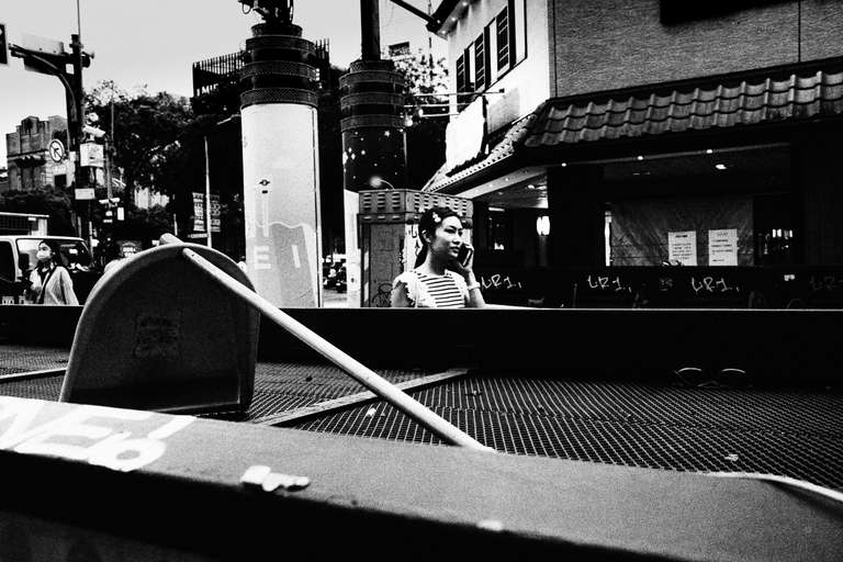 Black and white street photography. A picture of a woman on a call in the streets of Ximen, in Taipei, Taiwan.