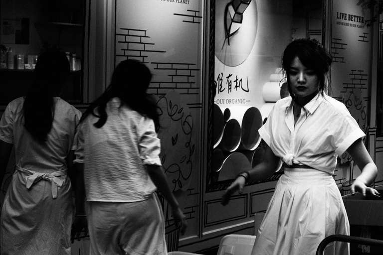 Black and white street photography. A picture of three young woman working, wearing white aprons in the streets of Taipei, Taiwan.